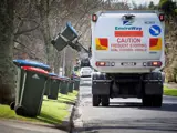 Rubbish truck picking up rubbish on the street.